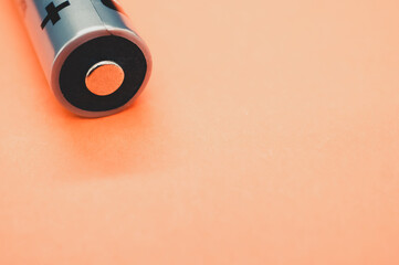 Closeup shot of a battery on a light orange background