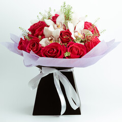 Bouquet with pink roses, orchids and colorful cymbidium in the box.