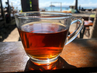 Black tea on the beachside table with sea background, nature light. Thailand