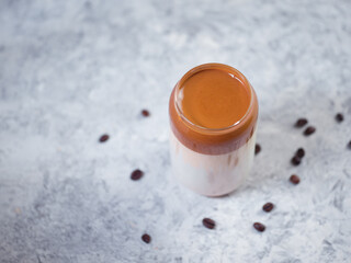 Dalgona coffee. Whipped Korean trend drink with coffee and milk. Creative glass, concrete white table