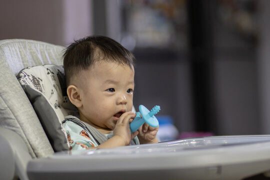 Potrait image of adorble and cute happy Asian Chinese baby boy sit on baby chair playing toy