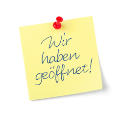 Yellow paper note with text  We are open in german - Wir haben geöffnet