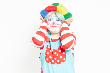 白背景の前で耳を隠すジェスャーをするピエロ