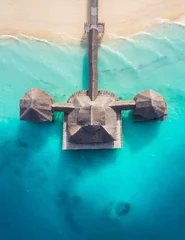 Zelfklevend Fotobehang Aerial shot of the Stilt hut with palm thatch roof washed with turquoise Indian ocean waves on the white sand sandbank beach on Zanzibar island, Tanzania. © Soloviova Liudmyla