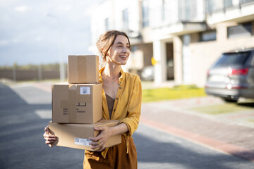Young happy woman carries home a parcels with goods purchased online at the modern residential...