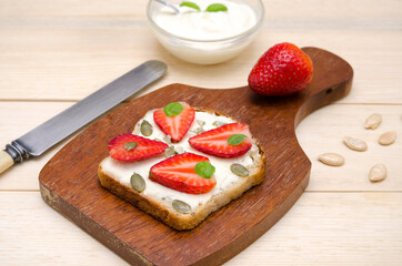 appetizing toast with cream cheese and strawberries and pumpkin seeds