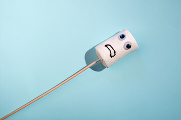 The concept of a summer barbecue. Funny marshmallow on sticks with eyes drawn mouth. Blue background. Top view.