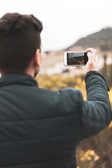 young man interacting with a mobile in the middle of the field