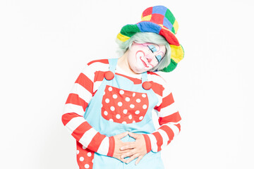 白背景の前に立って、お腹に手を当てるピエロ