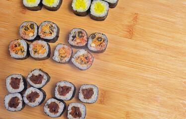 Sushi set lies on a wooden board, maki. Lots of sushi, rice, nori and filling, fish, seafood, place for food text