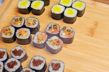 Sushi set lies on a wooden board, maki. Lots of sushi, rice, nori and filling, fish, seafood, place for food text