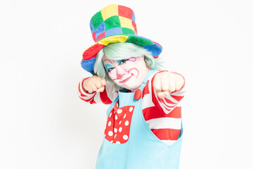 白背景の前に立って、パンチのジェスチャーをするピエロ