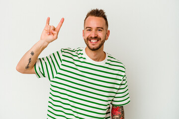 Fototapeta premium Young tattooed caucasian man isolated on white background showing a horns gesture as a revolution concept.