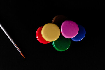 Top close up shot of oil color cans with a paint brush on black background.
