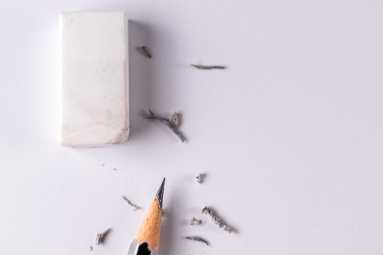 Top close up shot of an eraser with a pencil and waste left after erasing on white paper - Education concept.