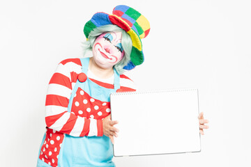 白背景の前に立って、大きいスケッチブックを持つピエロ