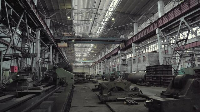 Interior of large workshop of metal processing plant with machine tools and moving industrial crane.