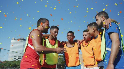 Colorful confetti falling against team of male soccer players discussing team strategy