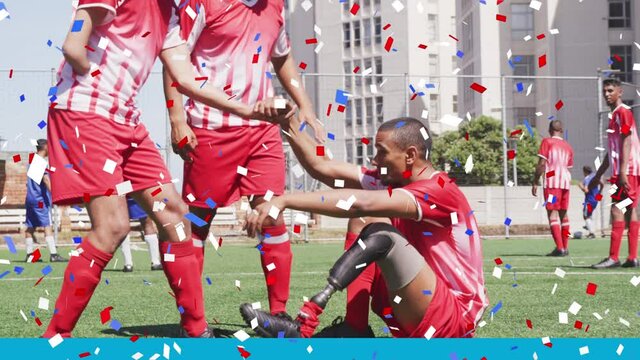 Colorful confetti falling against disabled male soccer player helping his teammate to get up