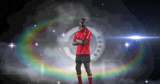 Animation of rugby player standing with arms crossed over glowing light with prism in background