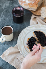 Woman spreading sweet jam on toast over table, top view. High quality photo