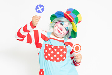 白背景の前に立って、OKとNGのプラカードを持つピエロ