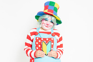 白背景の前に立って、初心者マークを持つピエロ