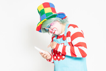 白背景の前に立って、電話を使うピエロ