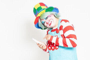 白背景の前に立って、電話を使うピエロ