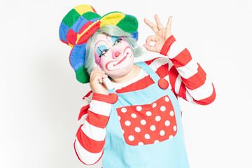 白背景の前に立って、電話を使うピエロ