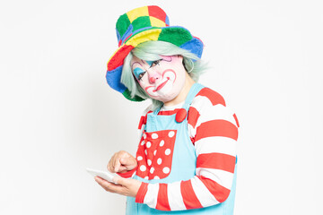 白背景の前に立って、電卓を使うピエロ