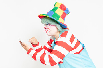 白背景の前に立って、電卓を使うピエロ