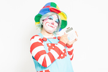 白背景の前に立って、電卓を使うピエロ