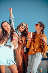 Three girls near the river against the sky having fun. Fashion girls in sunglasses. Jump, rejoice,...