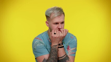 Panic attack. Upset scared frightened bearded adult guy biting nails, feeling worried nervous about serious troubles, stress and anxiety disorder, guilty. Young man on yellow studio wall background