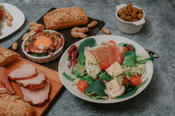 Festive table with meat, bread and snacks. Scrambled eggs with bacon, olives and vegan cutlets. Lunch or Dinner. Excellent breakfast. Salads and cheeses.