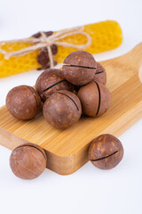 macadamia nuts in shell, on wooden board, on white background
