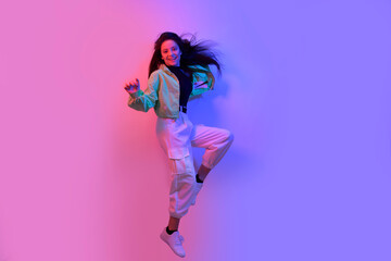 The brunette dancers in neon, the dancer in red and blue lights. Hip hop  party, smile. Model in flight, jumping. Bright photo, emotions.