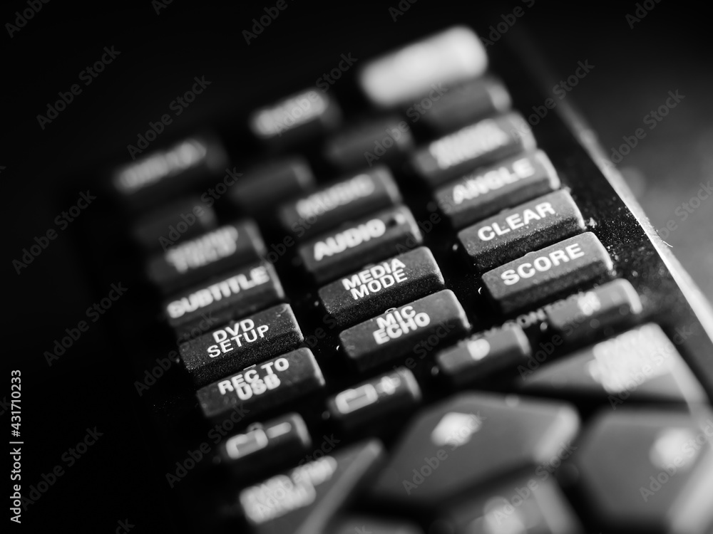 Poster selective focus shot of remote control with different buttons for the tv in the black background
