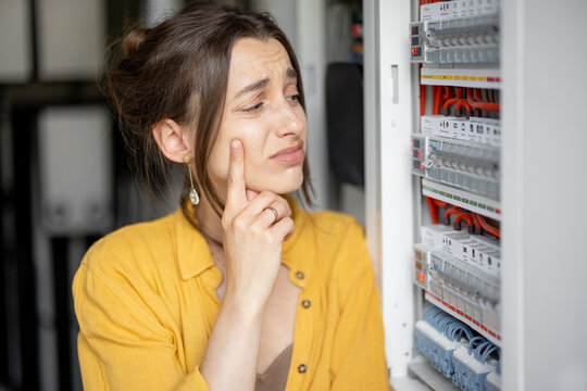 Confused woman having problems with electricity at home, speaks on the phone trying to solve the problem. Concept of female incompetence in home electricity