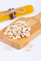 salted peanuts, halves with salt, on a wooden board, on a white background