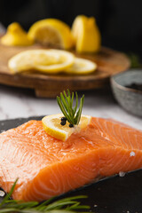 raw salmon with half a lemon and rosemary on the table