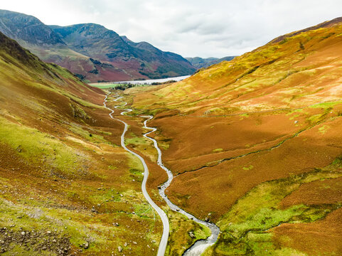 Aerial view of Honister Pass, a mountain pass with a road winding along Gatesgarthdale Beck mountain stream. Cumbria, the Lake District, England.