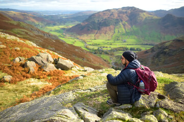 Male tourist enjoying sunset view of Great Langdale valley in the Lake District, famous for its glacial ribbon lakes and rugged mountains.