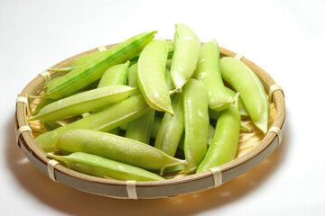 ざるに盛られたさやに入ったグリンピース