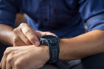 businessman wearing digital smart watch in hand  touching screen to open notification, read message and activity tracker in wrist with soft-focus and over light in the background.