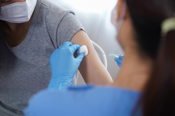 Obraz premium Close up doctor or nurse in medical mask holding syringe and using cotton before make inject vaccine to patient Covid-19 or coronavirus people vaccination to prevent infection and pandemic 