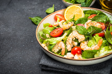 Shrimp salad with green leaves at stone table.
