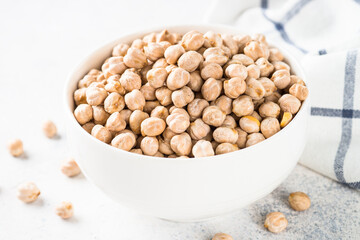 Chickpeas in white bowl at light kitchen table.