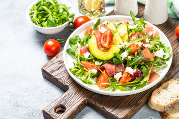 Fresh salad with green leaves, jamon and tomatoes.
